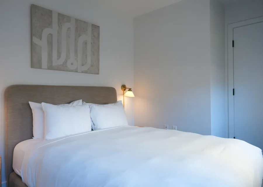 Chambre La Longère : lit bien fait, œuvre au mur