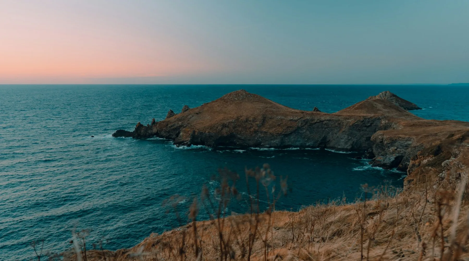 Pointe rocheuse sur une mer calme à l'heure bleue