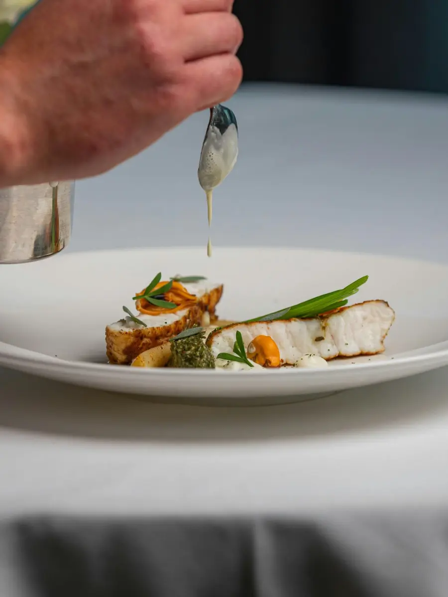 Le chef nappe un poisson de beurre blanc